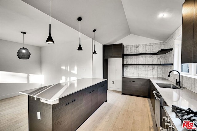 kitchen featuring light hardwood / wood-style floors, decorative light fixtures, sink, dark brown cabinetry, and a center island