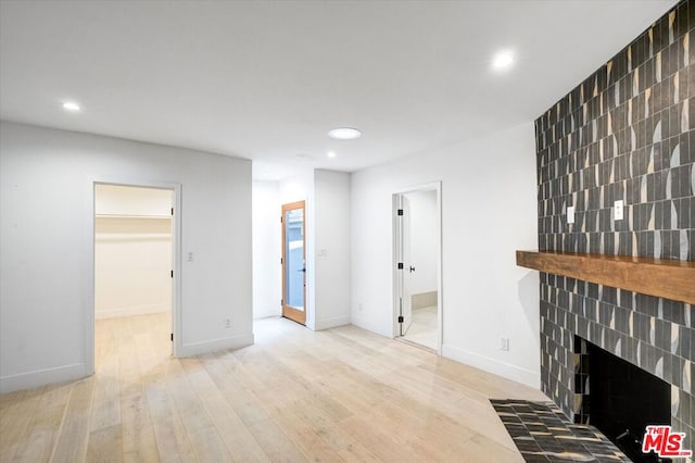 living room with light wood-type flooring and a tiled fireplace