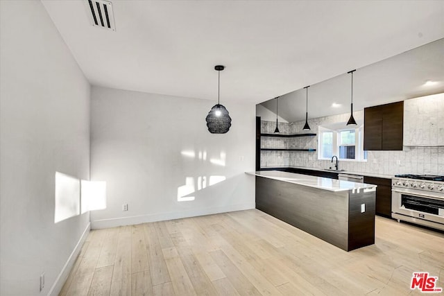 kitchen with appliances with stainless steel finishes, dark brown cabinetry, decorative light fixtures, sink, and backsplash