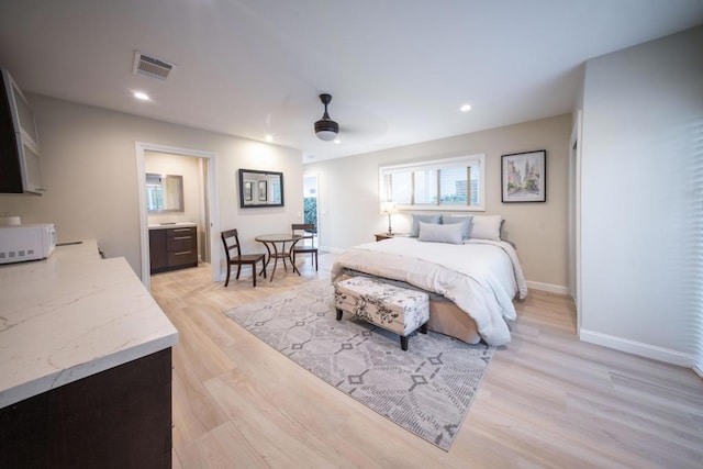 bedroom with ceiling fan, connected bathroom, and light wood-type flooring