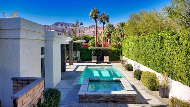 view of swimming pool featuring a mountain view, an in ground hot tub, and a patio