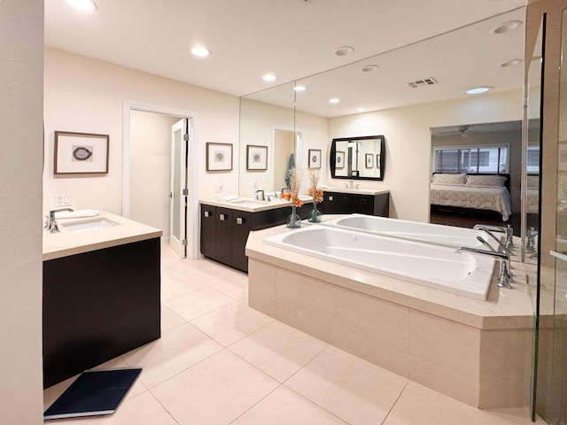 bathroom featuring tiled bath, vanity, and tile patterned flooring