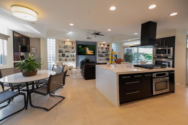 kitchen with ceiling fan, a center island, light tile patterned flooring, stainless steel appliances, and island range hood