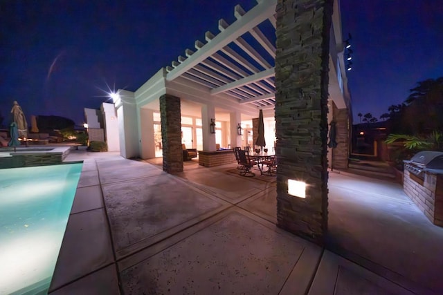 pool at night featuring a patio area, grilling area, and area for grilling