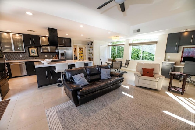 living room with ceiling fan, sink, and light tile patterned flooring