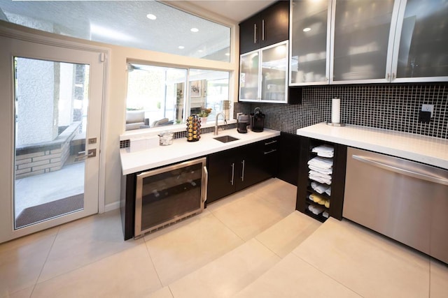 kitchen with backsplash, light tile patterned flooring, beverage cooler, stainless steel dishwasher, and sink