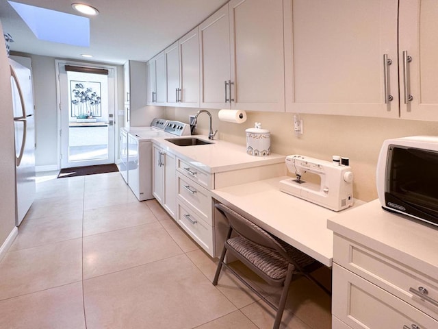 washroom with washer and clothes dryer, a skylight, sink, and light tile patterned flooring