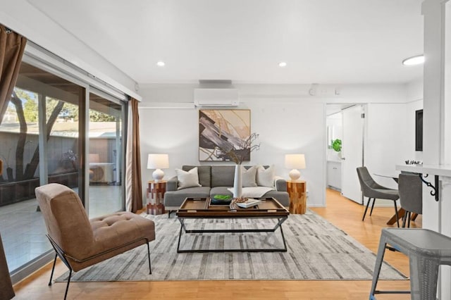 living room with an AC wall unit and light hardwood / wood-style flooring