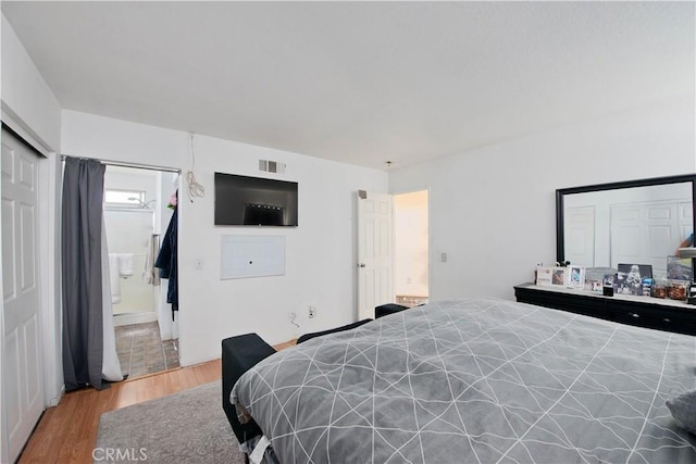 bedroom featuring ensuite bath and light wood-type flooring