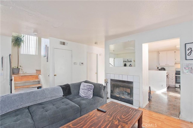 living room featuring a tile fireplace and light wood-type flooring