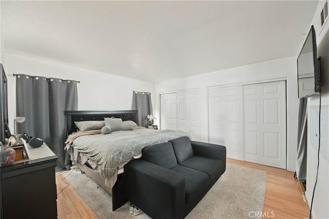 bedroom featuring two closets and light hardwood / wood-style floors