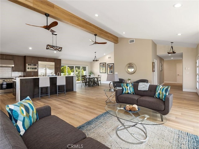 living room with ceiling fan, light hardwood / wood-style floors, and vaulted ceiling with beams