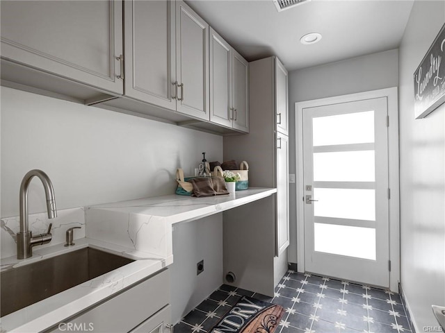 washroom with electric dryer hookup, sink, and cabinets