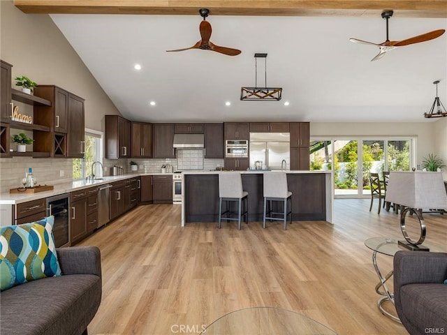 kitchen with wine cooler, decorative light fixtures, a center island, and appliances with stainless steel finishes