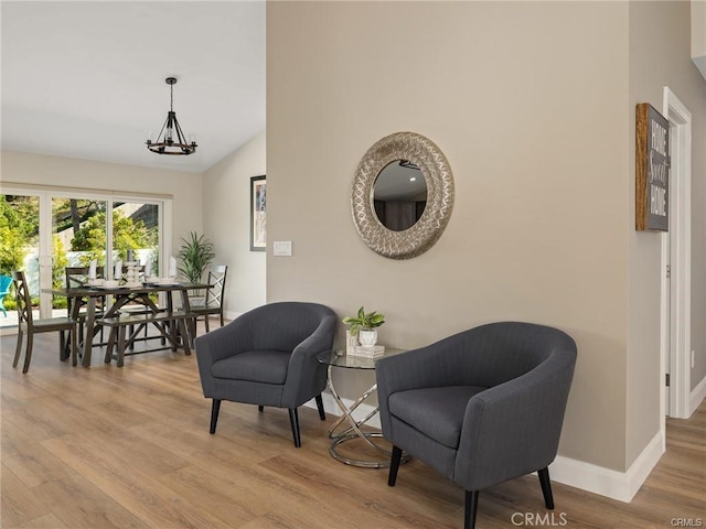 living area featuring lofted ceiling, a chandelier, and light hardwood / wood-style flooring