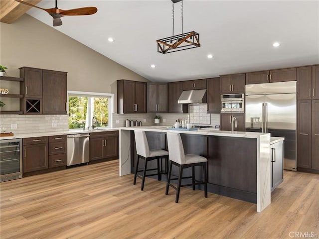 kitchen with wine cooler, a kitchen bar, sink, stainless steel appliances, and light hardwood / wood-style floors