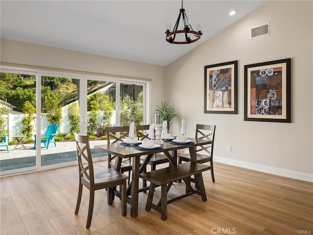 dining space with lofted ceiling, light hardwood / wood-style flooring, and a chandelier