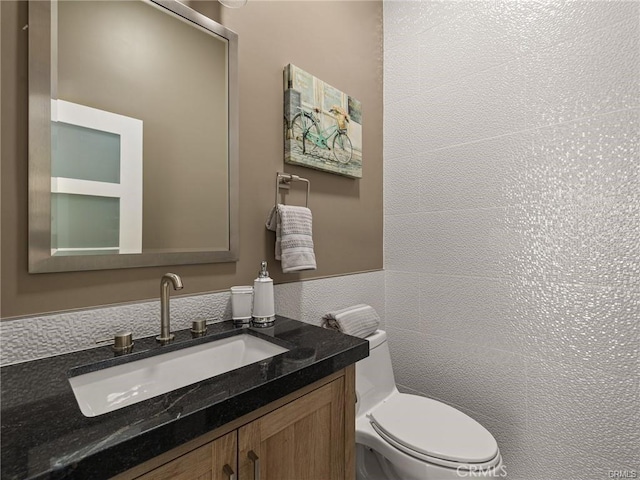 bathroom with vanity, tile walls, and toilet