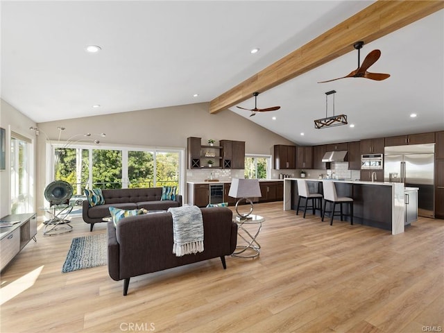 living room featuring vaulted ceiling with beams, a wealth of natural light, light hardwood / wood-style floors, and beverage cooler