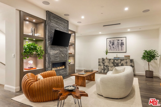 living room with hardwood / wood-style floors, built in features, and a fireplace