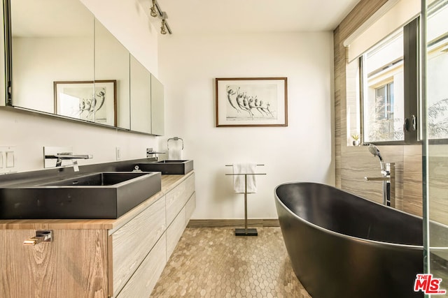 bathroom with a tub, rail lighting, vanity, and tile patterned flooring