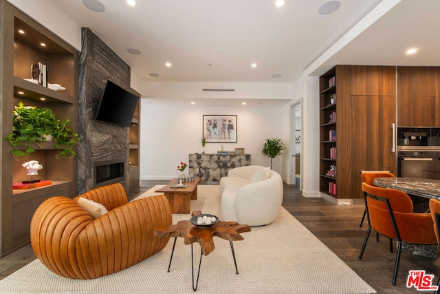 living room with built in shelves, a fireplace, and dark hardwood / wood-style flooring