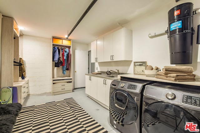 washroom featuring washing machine and dryer, cabinets, and sink