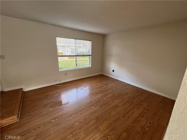 spare room with dark hardwood / wood-style floors and a textured ceiling