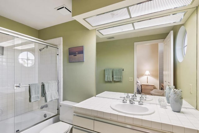 full bathroom featuring combined bath / shower with glass door, vanity, and toilet