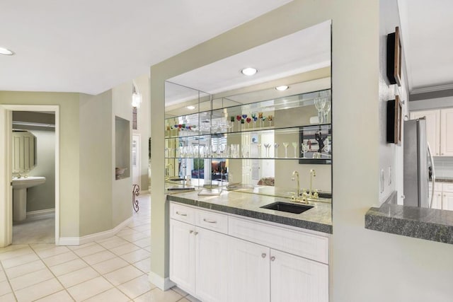 bar featuring light tile patterned flooring, white cabinets, stainless steel fridge, and sink