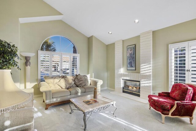 living room featuring plenty of natural light, a large fireplace, french doors, and light colored carpet