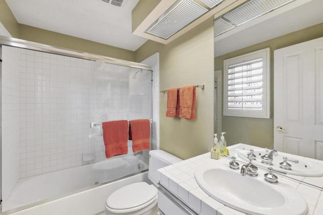 full bathroom with bath / shower combo with glass door, toilet, and vanity