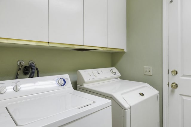 clothes washing area with cabinets and washing machine and clothes dryer