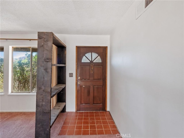 entrance foyer featuring a textured ceiling and dark colored carpet