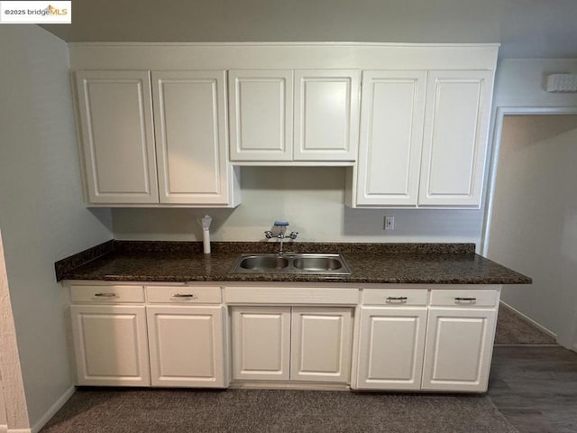 kitchen featuring white cabinets, sink, and dark colored carpet