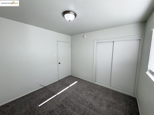 unfurnished bedroom with a closet and dark colored carpet