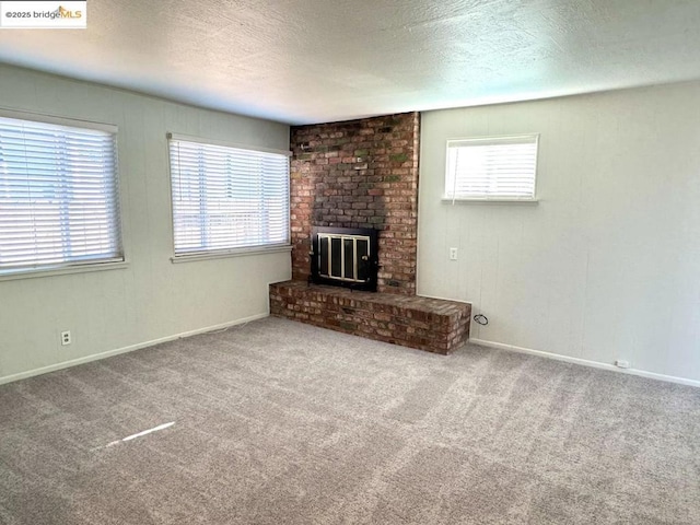 unfurnished living room featuring a brick fireplace, a textured ceiling, and carpet flooring