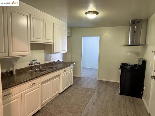 kitchen featuring wall chimney range hood, white cabinets, and range with gas stovetop