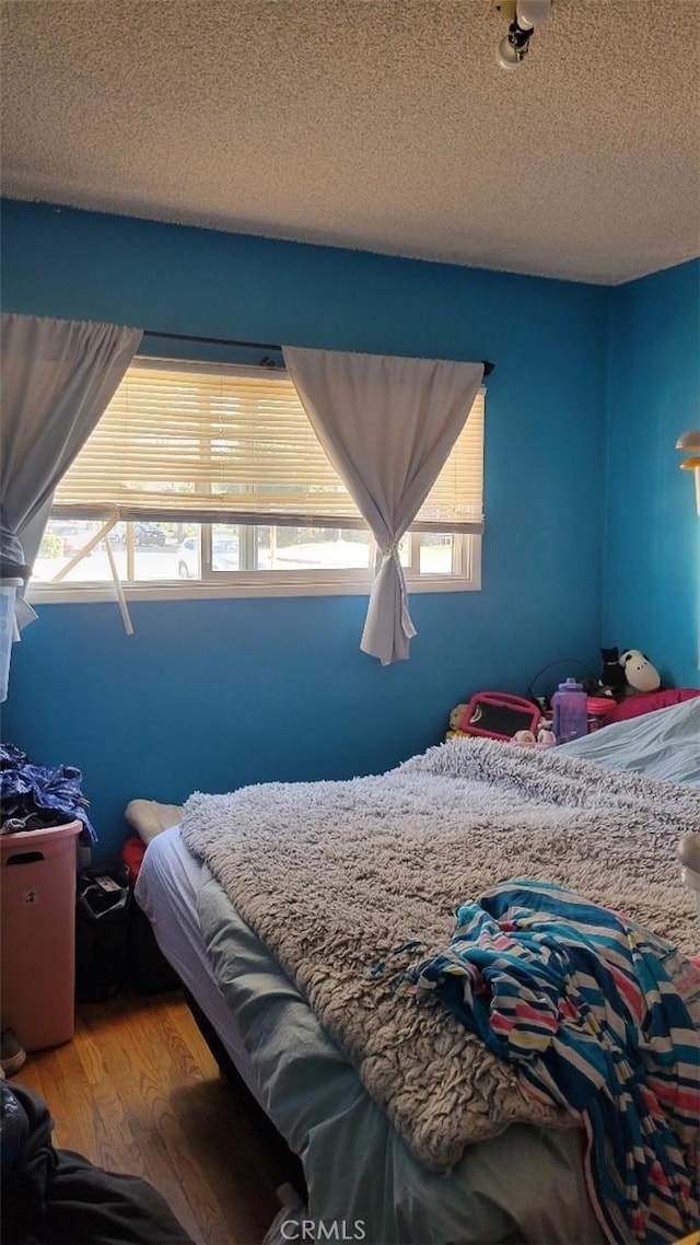 bedroom featuring a textured ceiling and hardwood / wood-style flooring