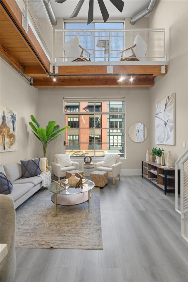 living room featuring hardwood / wood-style flooring, ceiling fan, and a high ceiling