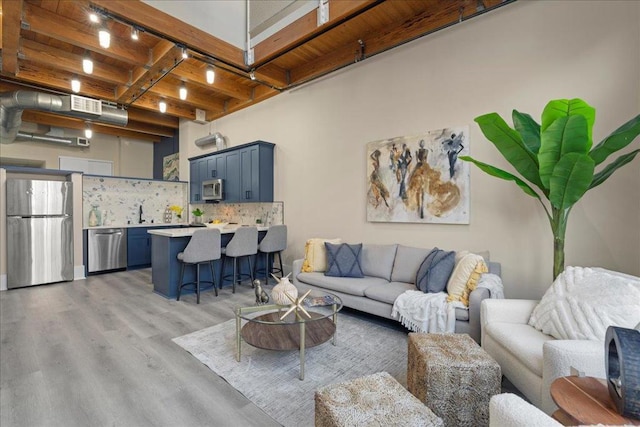 living room with rail lighting, wooden ceiling, beam ceiling, and light hardwood / wood-style flooring