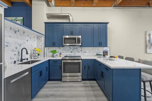 kitchen featuring sink, a kitchen bar, decorative backsplash, kitchen peninsula, and stainless steel appliances