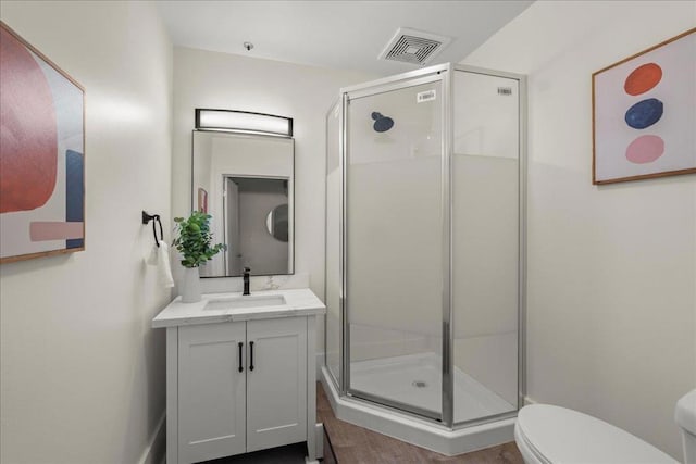 bathroom featuring vanity, a shower with door, and toilet