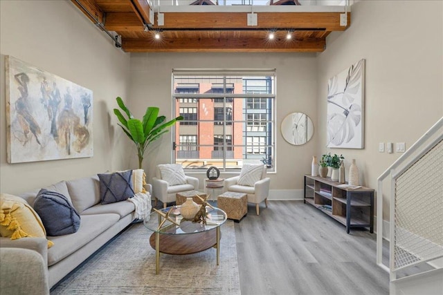 living room featuring beamed ceiling, track lighting, light wood-type flooring, and wooden ceiling