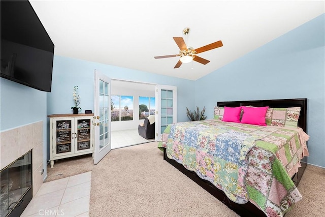 carpeted bedroom with a tiled fireplace, lofted ceiling, ceiling fan, and french doors