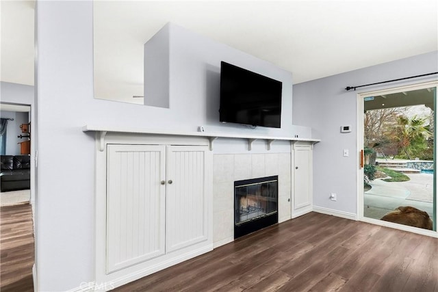 unfurnished living room featuring a tile fireplace and dark hardwood / wood-style flooring