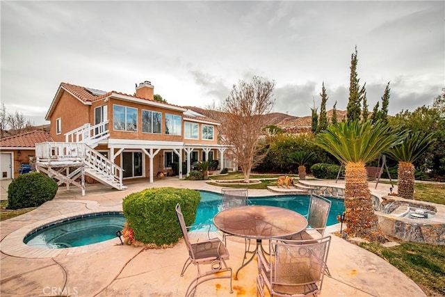 back of house featuring a swimming pool with hot tub and a patio