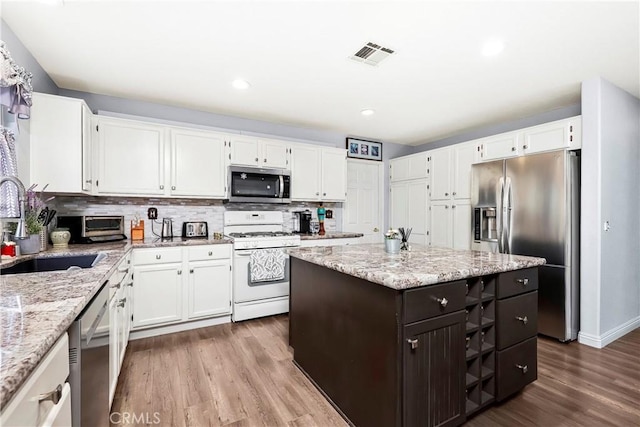 kitchen with appliances with stainless steel finishes, a center island, sink, and white cabinets