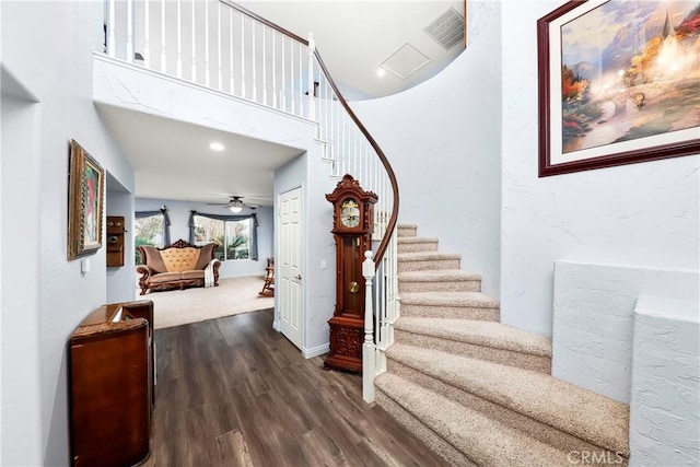 stairs featuring hardwood / wood-style flooring and a high ceiling