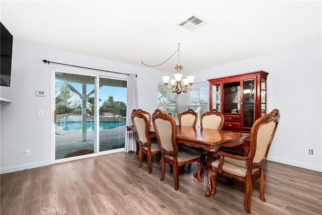 dining room featuring plenty of natural light, wood-type flooring, and a notable chandelier